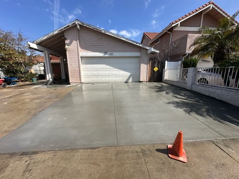 Finished concrete driveway at a pink stucco home in San Diego